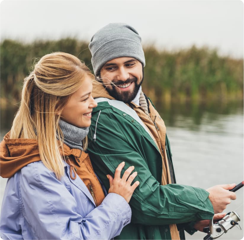 A man and woman fishing at a river's edge