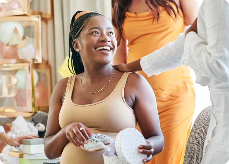 A woman opening a gifted pair of baby shoes at a baby shower