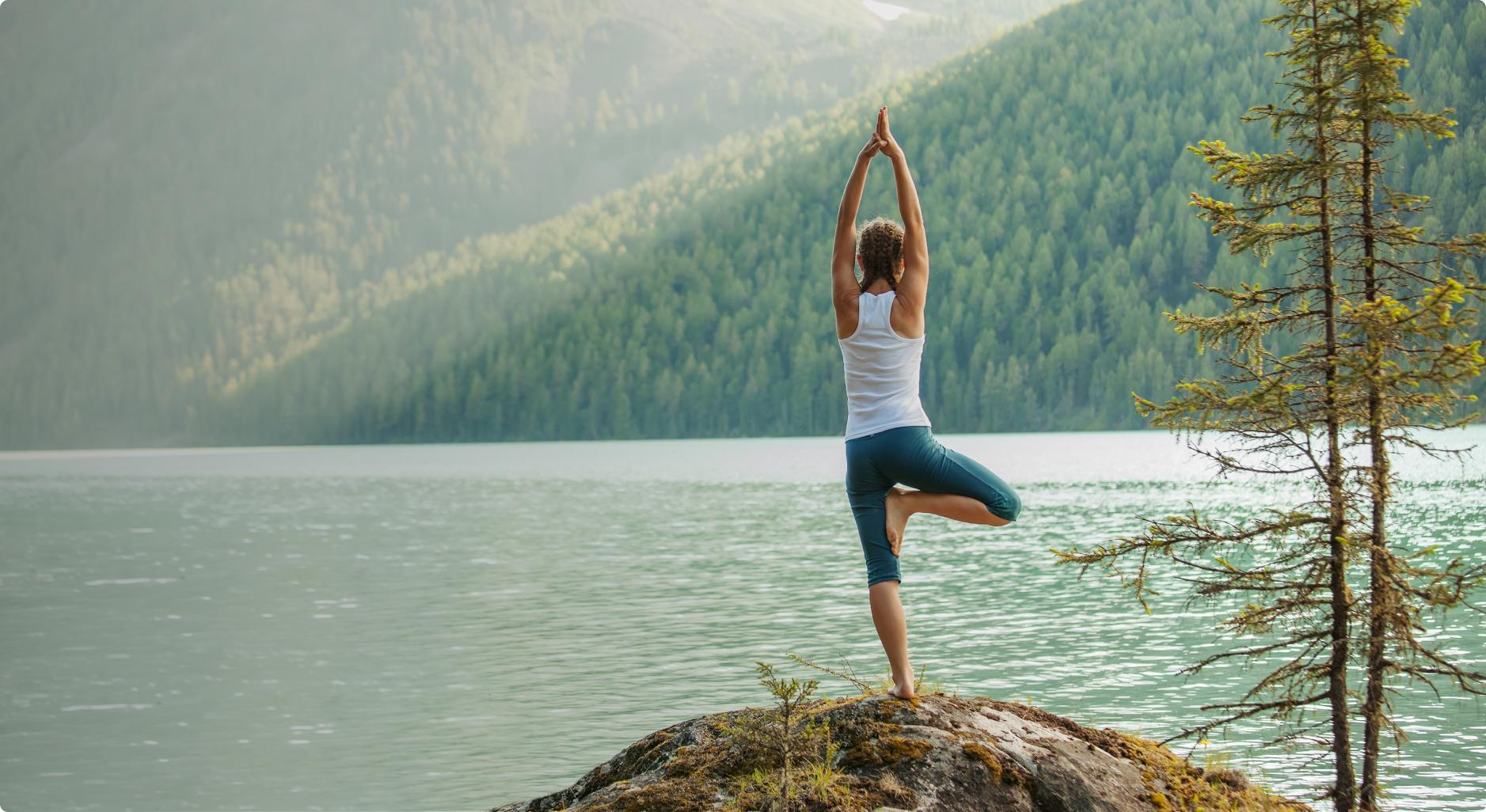 A woman practicing yoga by a lake