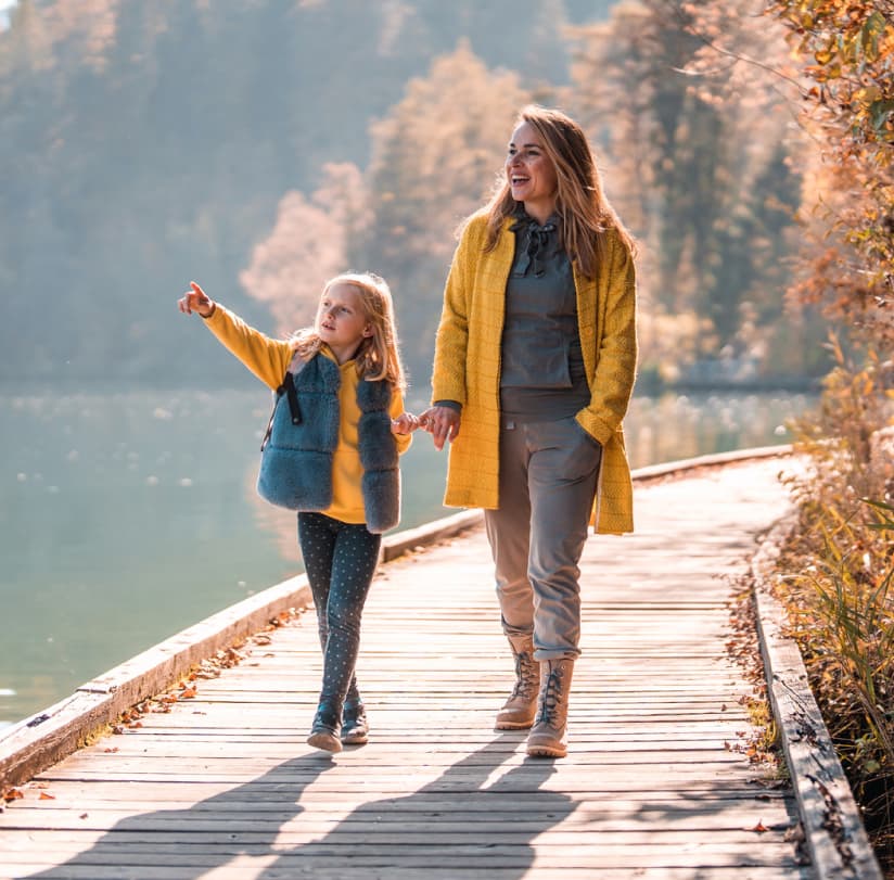 A mother and her daughter walking near a lake