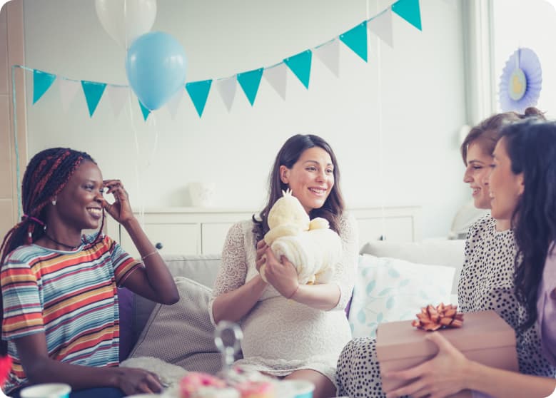 A woman at a baby shower smiling and holding a gift